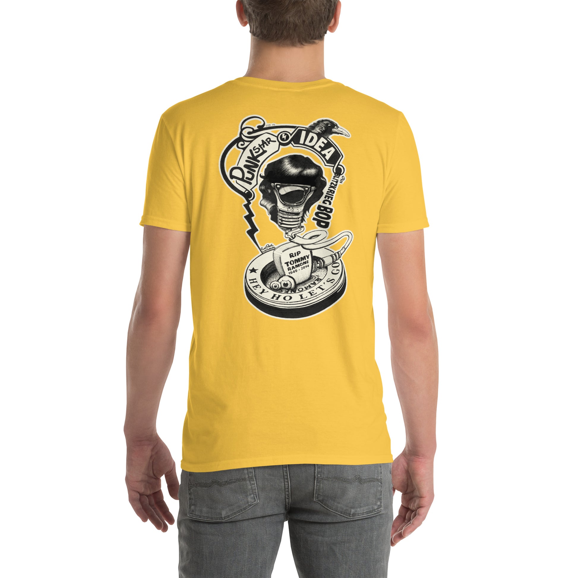 chico con camiseta color amarillo margarita de espalda con ilustración de bombilla Tommy Ramone cuervo y las letras punk star idea y hey ho let's go en la espalda